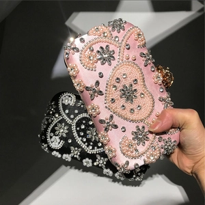 Close-up of luxury satin evening bag with handcrafted pearl and rhinestone floral embroidery
