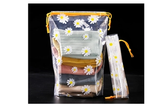 Frosted daisy drawstring bag with yellow cord showing stored items on black backdrop