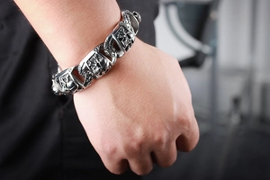 Detailed view of heavy vintage silver skull link bracelet worn on a male wrist