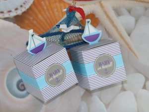 Detail of nautical baby shower favor boxes with blue stripes and sailboat toppers