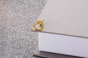 Close-up of a minimalist hollow heart-shaped stud earring in a gold metallic finish