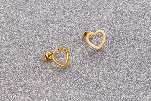 Detail view of hollow heart stud earrings in shiny gold finish on textured background