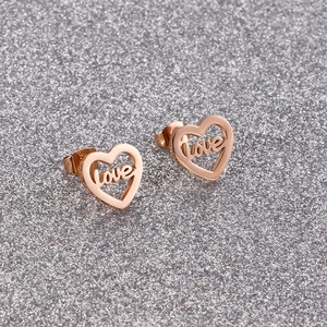 Rose gold heart-shaped love stud earrings on a textured silver glitter background