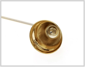 Macro shot of the interior of a golden candle snuffer bell with silver clapper detail