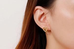 Close-up of golden heart-shaped love earrings worn by a model in a minimalist style