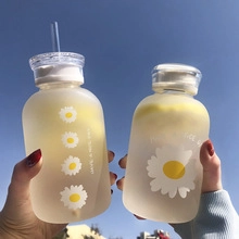 Gros plan de gobelets en verre dépoli avec imprimés marguerites et citrons sous le ciel bleu