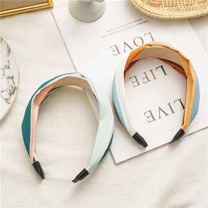 Detail of two cross-knot fabric headbands in vibrant color-block patterns on a magazine