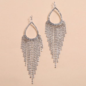 Sparkling silver teardrop fringe earrings with rhinestones on a beige background