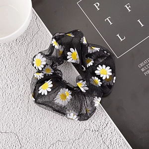 Detail of black mesh scrunchie with white daisy prints on light organza fabric