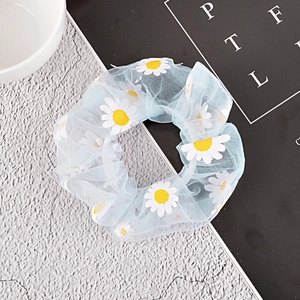 Detail of light blue mesh scrunchie with daisy print on stone and book background