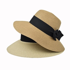 Detail of woven straw sun hats in beige and tan with elegant black ribbon bows