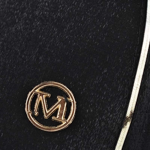 Close-up of black plaid baseball cap featuring a golden M logo and metallic stripe