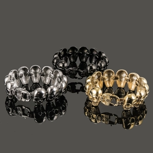 Detailed macro shot of three punk style stainless steel skull bracelets in silver gold and black