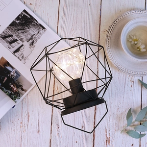 Industrial black geometric metal iron LED lamp with warm glass bulb on white wooden desk
