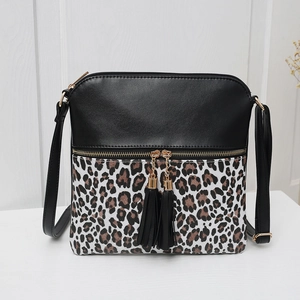 Detail of crossbody bag with leopard print panel, golden zipper, and dual tassel pendants