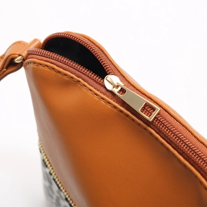 Detailed close-up of smooth gold metal zipper and stitching on leopard print purse