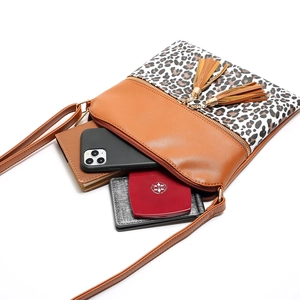 Detail of crossbody bag with leopard print, twin tassels, and spacious inner storage