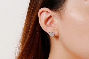 Close-up of a silver elephant stud earring with a small zircon eye on a model's ear