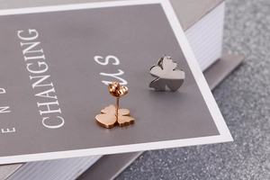 Macro shot of stainless steel butterfly and clover stud earrings in rose gold and silver
