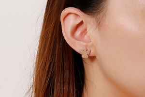 Close-up of minimalist angel stud earrings in rose gold finish on a female model