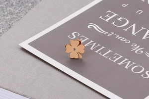 Macro shot of a rose gold clover stud earring with a clear crystal on a grey card