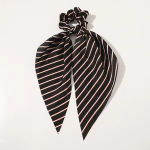 Close-up of smooth satin scrunchie with red and white diagonal stripes on black