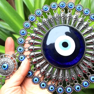 Blue Evil Eye metal wall hanging decor with sunburst silver patterns held by hand