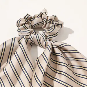 Detailed close-up of striped satin scrunchie with a smooth champagne and blue finish