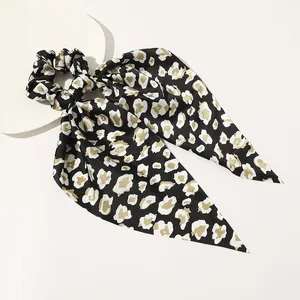 Detailed close-up of leopard print satin hair scrunchie with long ribbon tails