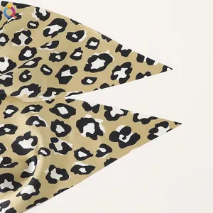 Detailed macro view of leopard print satin fabric with smooth silk texture and golden finish