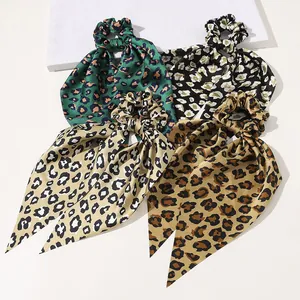 Detailed view of four leopard print satin scrunchies with long ribbons in diverse colors