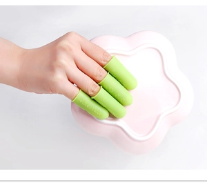 Close-up of green silicone finger guards with non-slip texture on a pink tray