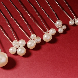 Silver wavy metal hair pins set with white pearls on a deep red textured background