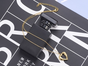 Close-up of golden heart-shaped wing pendant with K18 engraving on a minimalist chain