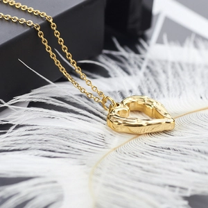 Gold heart pendant necklace with hammered texture on a black gift box background