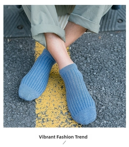 Detail of blue rib-knit low cut ankle socks for men shown on asphalt street background
