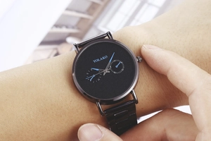Men's thin black watch with blue hands and dual sub-dials on a stainless steel strap