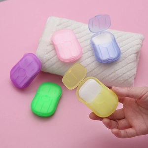 Portable colorful soap paper sheets in mini travel containers on a soft white towel