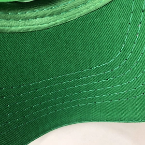 Macro detail of high-quality green baseball cap brim with parallel stitching on twill cotton