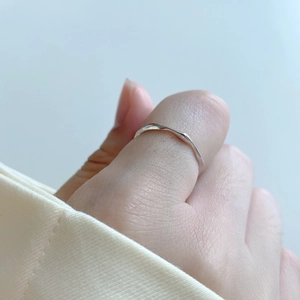 Minimalist 925 sterling silver irregular wavy ring shown on thumb with natural light