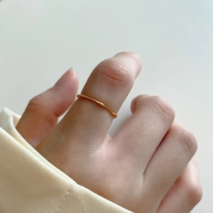 Close-up of minimalist wavy golden ring on hand showing the sleek irregular design