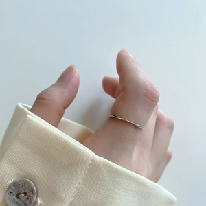 Close-up of minimalist S925 sterling silver irregular wavy thin ring worn on a finger