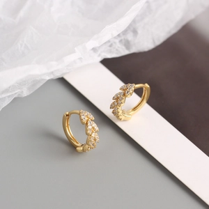 Détails de boucles d'oreilles feuilles dorées avec pavage de zircons blancs brillants