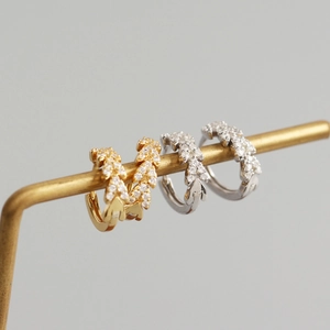 Vue macro des boucles d'oreilles feuilles en argent et or avec pierres en zircone cubique