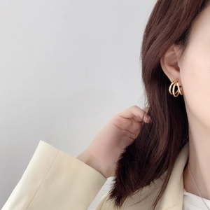 Detail of French style layered gold hoop earrings on female model with minimalist suit