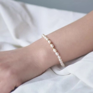 Elegante bracciale di perle d'acqua dolce con perle dorate su sfondo di raso morbido