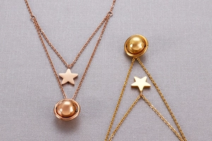 Detail of star and planet pendants on layered necklaces in rose gold and gold finish