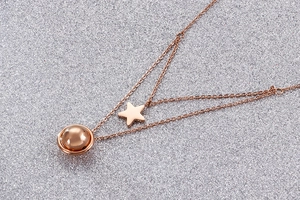 Close-up of double-layer rose gold necklace featuring star and round sphere pendants