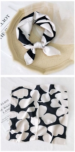 Detail of black and white floral silk scarf showing both knotted and flat satin texture