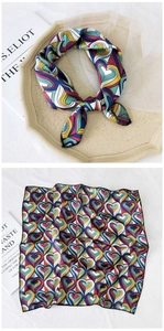 Close-up of heart-patterned square silk scarf in red and blue, styled with elegant props